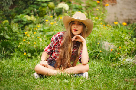 beautiful young girl with long hair sit on grassの写真素材