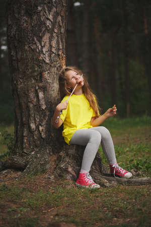 girl eats sausage in summer forestの写真素材