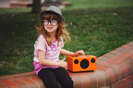little hipster girl listens music on wireless retro looking spea