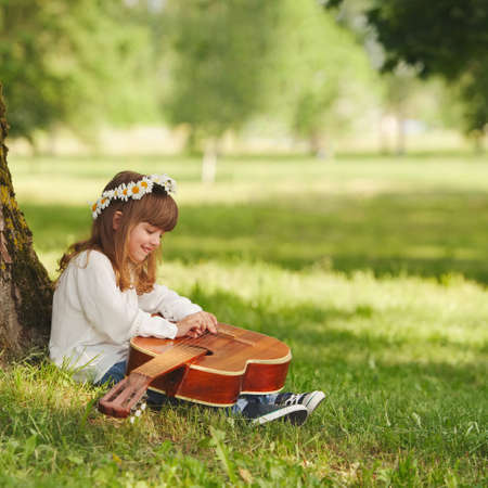 boy and girl playing guitar in summer parkの写真素材
