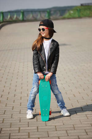 little girl with skateboard on the streetの写真素材