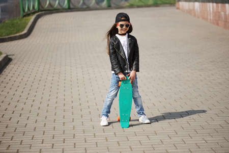 little girl with skateboard on the streetの写真素材