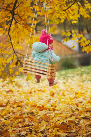 little girl on swings in autumn park
