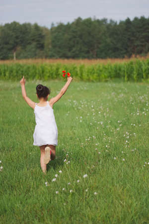 cute little girl with poppy in summer fieldの写真素材