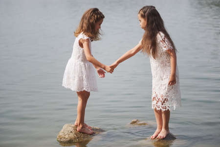 cute happy little girls in sumer lakeの写真素材