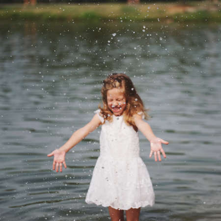cute happy little girls in sumer lakeの写真素材
