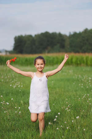 little girl with poppy in summer fieldの写真素材