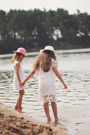 cute happy little girls in sumer lakeの写真素材