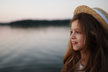 little cute girl with long hair on the lakeの写真素材