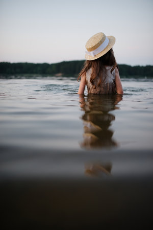 little cute girl with long hair on the lake