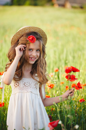 cute little girl in meadow with red poppiesの写真素材