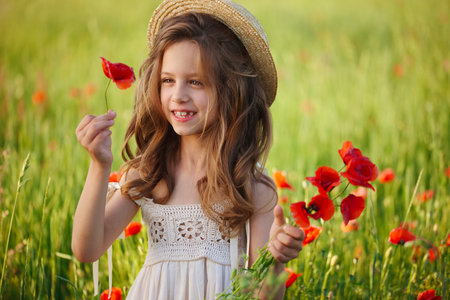 cute little girl in meadow with red poppiesの写真素材