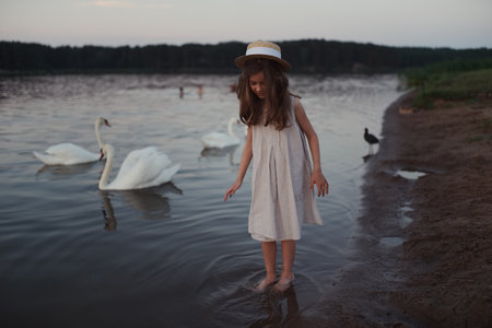 little cute girl with long hair on the lakeの写真素材