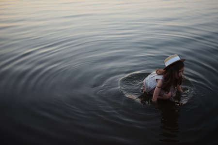 little cute girl with long hair on the lakeの写真素材
