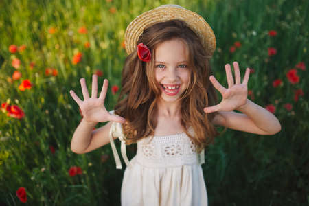 cute little girl in meadow with red poppiesの写真素材