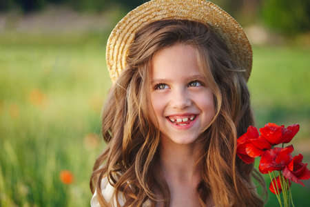 cute little girl in meadow with red poppiesの写真素材