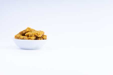Fried tempeh or soybean cake in white bowl over a white background. It is made by fermentation process that binds soybeans into a cake formの写真素材