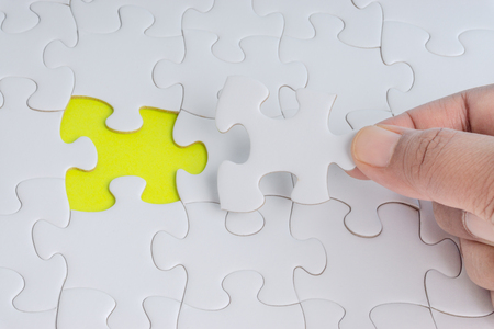 Hand put the last piece of jigsaw puzzle closeup to complete the mission. Selective focus and crop fragmentの写真素材