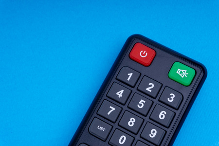 Remote control TV or radio isolated on blue background with selective focus and crop fragment