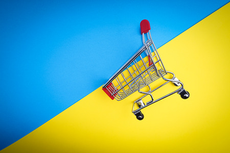 Shopping cart on blue and yellow background, business and shopping concept. Selective focusの写真素材