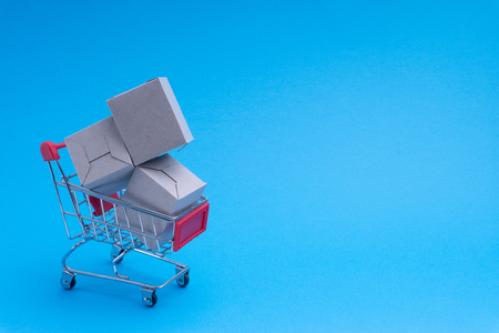 Shopping cart and box on blue background, business and shopping concept. Selective focusの写真素材