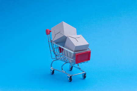 Shopping cart and box on blue background, business and shopping concept. Selective focusの写真素材