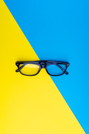 Black frame eyeglasses on blue and yellow background
