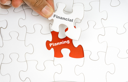 Hand holding piece of jigsaw puzzle with word FINANCIAL PLANNING. Selective focusの写真素材