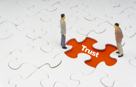 TRUST inscription written on jigsaw puzzle and businessman miniature. Business and motivation conceptの写真素材