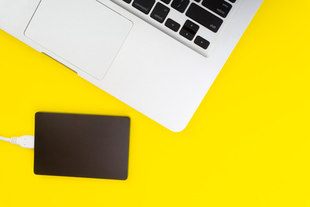 Laptop keyboard, storage drive or hard disk on yellow background with selective focus, crop...