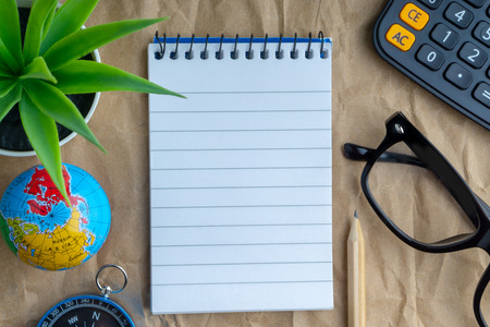 Notepad, flower vase, spectacle, pencil , compass, globe, calculator on wooden paper background. Business and education conceptの写真素材