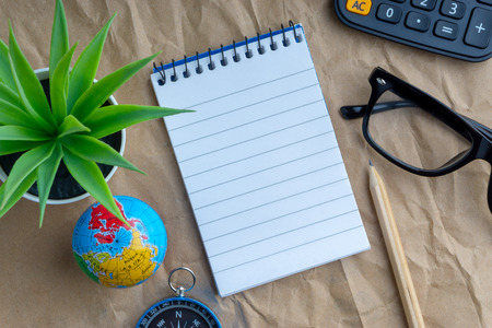 Notepad, flower vase, spectacle, pencil , compass, globe, calculator on wooden paper background. Business and copy space conceptの写真素材