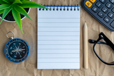 Notepad, flower vase, spectacle, pencil , compass, calculator on wooden paper background. Business and copy space conceptの写真素材