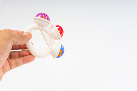 Hands hold rattle toy or baby toy on white background. Selective focus