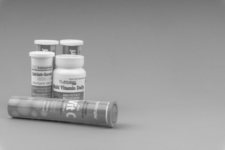 KUALA LUMPUR, MALAYSIA - APRIL 15, 2019 : Multivitamin tablets and Vitamin C container on black and white. Selective focus and crop fragmentのeditorial素材