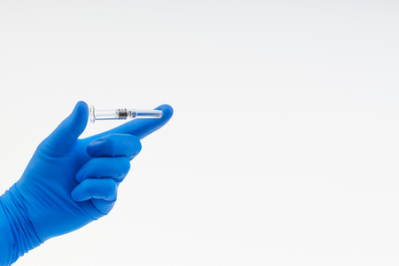 Hand in a blue glove holding syringe isolated on whiteの写真素材