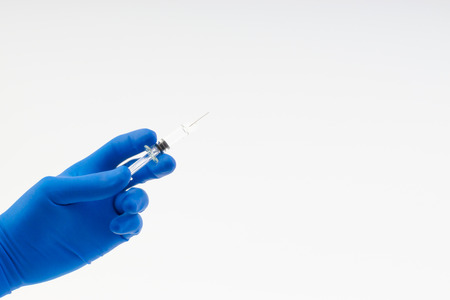 Hand in a blue glove holding syringe isolated on whiteの写真素材