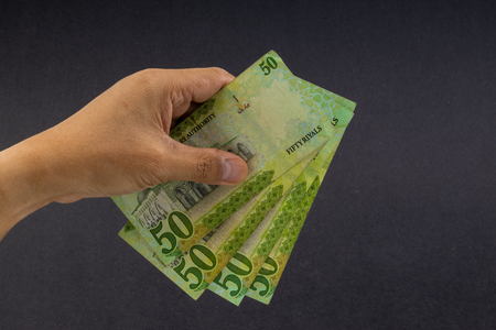 Hand holding saudi riyal bank notes on black background. Financial concept and selective focus