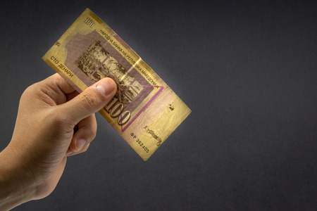 Hand holds one hundred MACEDONIA CURRENCY, Macedonian denar Bank note on black background. Selective focusの写真素材