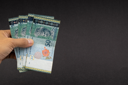 Hand holding Malaysia Ringgit MYR Currency Bank Notes. Selective focus