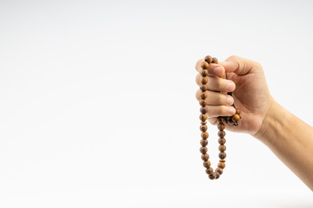 Hand holding a muslim rosary beads or Tasbih on white background. Copy space and selective focusの写真素材