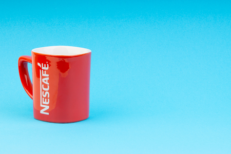 Kuala Lumpur, Malaysia - July 03, 2019:  Promotional red Nescafe mug on blue background. Selective focusのeditorial素材
