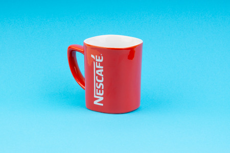 Kuala Lumpur, Malaysia - July 03, 2019:  Promotional red Nescafe mug on blue background. Selective focusのeditorial素材