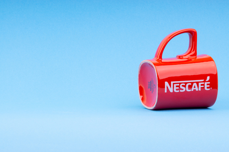 Kuala Lumpur, Malaysia - July 03, 2019:  Promotional red Nescafe mug on blue background. Selective...