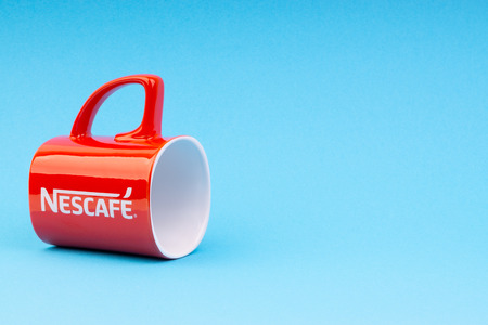 Kuala Lumpur, Malaysia - July 03, 2019:  Promotional red Nescafe mug on blue background. Selective focusのeditorial素材