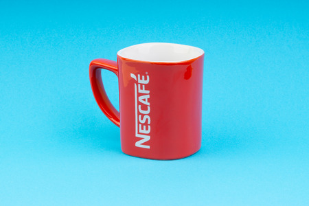 Kuala Lumpur, Malaysia - July 03, 2019:  Promotional red Nescafe mug on blue background. Selective focusのeditorial素材