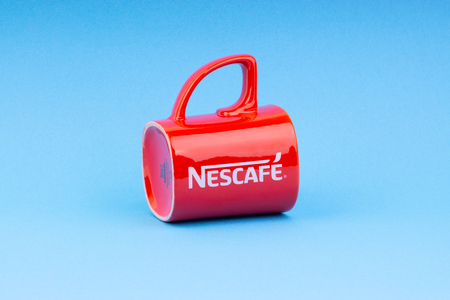 Kuala Lumpur, Malaysia - July 03, 2019:  Promotional red Nescafe mug on blue background. Selective focusのeditorial素材