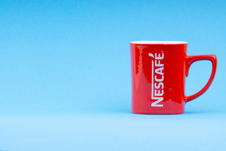 Kuala Lumpur, Malaysia - July 03, 2019:  Promotional red Nescafe mug on blue background. Selective focusのeditorial素材