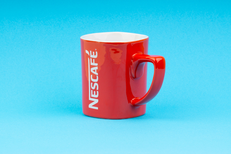 Kuala Lumpur, Malaysia - July 03, 2019:  Promotional red Nescafe mug on blue background. Selective focusのeditorial素材