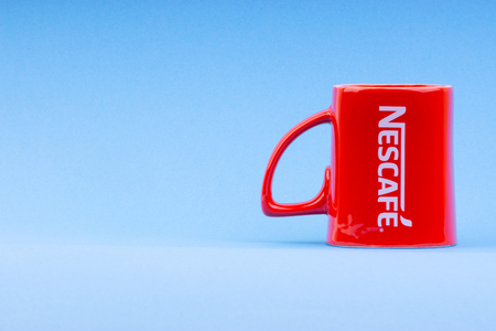 Kuala Lumpur, Malaysia - July 03, 2019:  Promotional red Nescafe mug on blue background. Selective focusのeditorial素材